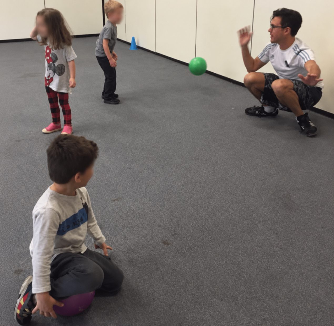 Coach Matt crouching at eye level with preschoolers during a soccer game