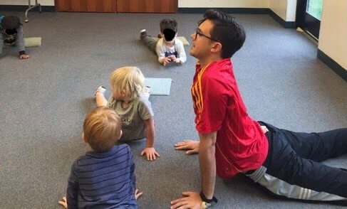 Coach Matt leading preschoolers through a yoga pose