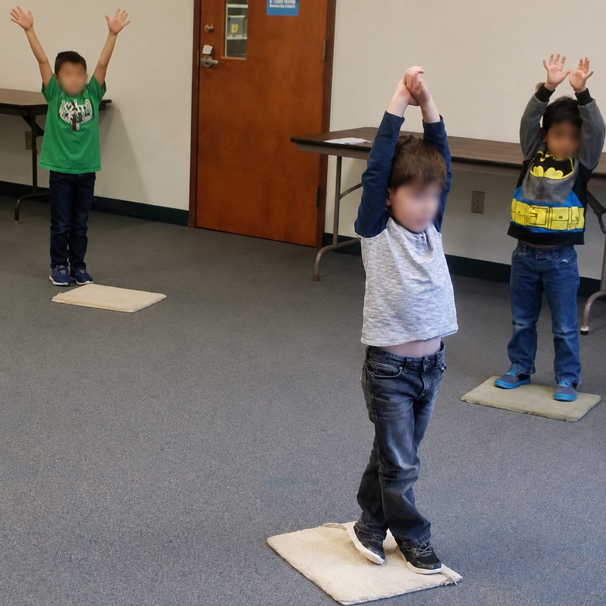 Preschoolers standing on mats with arms stretched overhead during the yoga portion